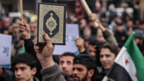 Un manifestante alza un Corn en Idlib (Siria) en una protesta tras la quema de los libros sagrados del islam en Europa.