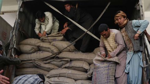 Trabajadores afganos descargan sacos de trigo, proporcionados por la India, en Herat