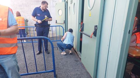 Una opositora, este sbado, dejando el mvil en la rendija de una de las puertas de acceso al pabelln de las oposiciones, ante la mirada de uno de los guardias de seguridad.