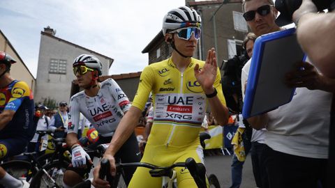 Imagen de Pogacar en la que se lo ve con el pinganillo en el oído, el miniordenador en el manillar de la bici y observando datos en una tableta.