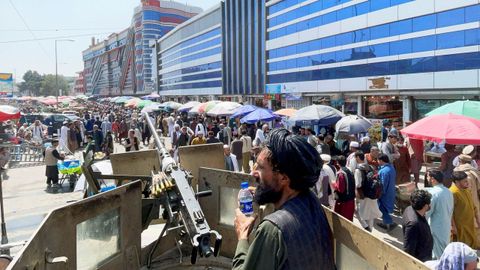 Un talib�n fuertemente armado vigila a la multitud ante un mercado de cambio de divisas en Kabul.