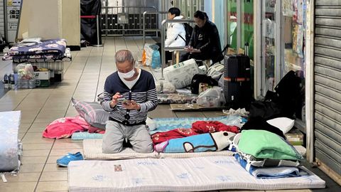 Afectados por el incendio en el complejo residencial de Hong Kong descansan en un centro comercial