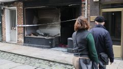 Viandantes contemplando en la ma�ana de este lunes el aspecto exterior del bajo�tras el incendio sufrido.