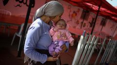 Una chica de 25 a�os besa a su hija en un centro de atenci�n al migrante.