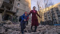 Una mujer con un ni�o evacua de un edificio residencial da�ado por los bombardeos,