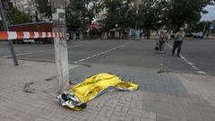 Dos peatones observan el cad�ver cubierto de una de las v�ctimas del ataque con bombas racimo en Mykolaiv