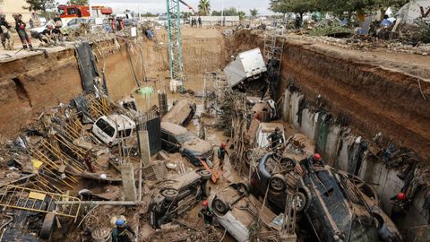 Expertos de la Guardia Civil buscan cuerpos sin vida entre los vehculos atrapados entre los cimientos de un edificio en construccin en Paiporta, Valencia