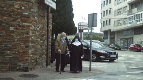 Imagen de una monja trasladando a una persona mayor a votar