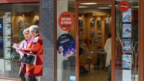 Dos mujeres miran su documentacin delante de la agencia de Halcn Viajes de la calle Progreso de Lugo