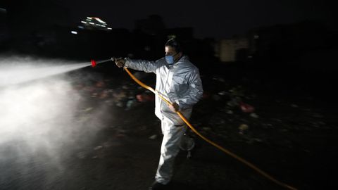 Un voluntario desinfecta una calle en Yemen durante la noche