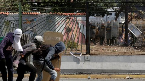 Un grupo de opositores se protege frente a agentes de la Guardia Nacional Bolivariana