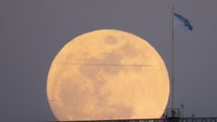 La luna llena sale sobre una bandera de Galicia en Santiago de Compostela