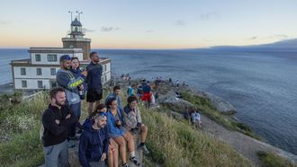 Turistas disfrutan del atardecer junto al faro de Fisterra
