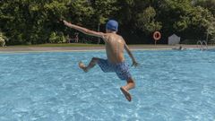 En foto de archivo, un joven se divierte saltando en una piscina.
