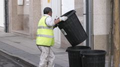 Un trabajador de FCC en Monforte pone los cubos de basura en una calle de Monforte