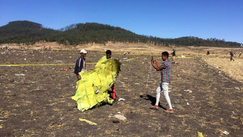 Un civil sujeta parte del fuselaje del avin accidentado mientras es fotografiado