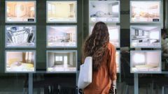 Una joven consulta las ofertas de pisos en el escaparate de una inmobiliaria