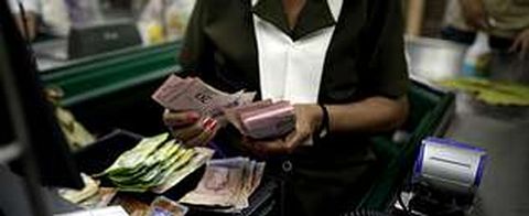 Una cajera cuenta bol�vares en un supermercado de Caracas