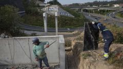 Dos operarios, trabajando este viernes en el punto de entronque de las pasarelas con el trazado hacia Conxo. En el centro de la imagen se ven ya rematados los dos pilares que sustentar�n esas estructuras