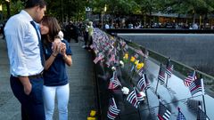 Katie es consolada por su pareja ante la placa donde figura su padre el bombero Joseph Mascali. 