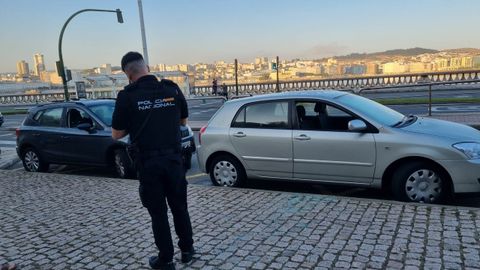 Un agente de la Polica Nacional delante de dos de los vehculos que aparecieron en la zona de la Domus con las ventanillas rotas