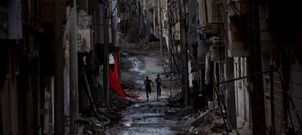 Unos j�venes corren por las ruinas en que ha convertido la guerra la ciudad de Deir al Zor, en una provincia del este de Siria.