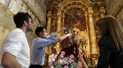 Unos cofrades miran con preocupación la talla de la Virgen de Montserrat una vez terminada la procesión
