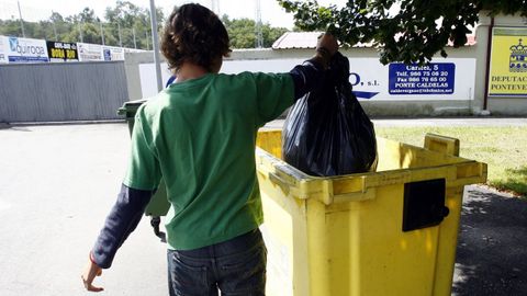 Un joven deposita una bolsa en el contenedor amarillo