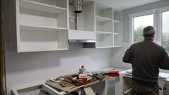 Un carpintero trabajando en la reforma de una cocina. 