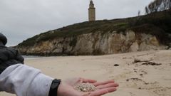 Diminutas bolitas de pl�stico recogidas en la playa de As Lapas, en A Coru�a, con la Torre de H�rcules al fondo