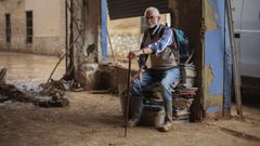 Donis, de la librera La Moixeranga de Paiporta, sentado sobre algunos ejemplares en su local arrasado por las riadas.