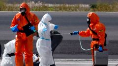 Un pasajero del crucero MV Hondius se desinfecta en la pista del aeropuerto de Tenerife Sur, al desembarcar del buque.