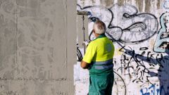 Un trabajador de la concesionaria municipal de limpieza viaria tapa una pintada