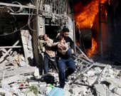 Dos hombres evac�an a dos ni�os en un edifico alcanzado por barriles bomba en Alepo.