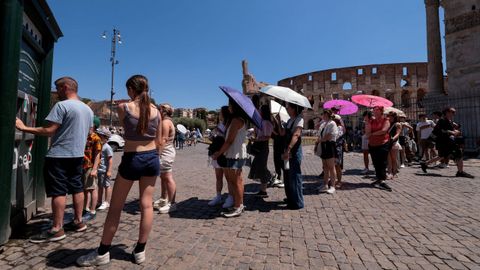 Un grupo de turistas se protegen del sol con paraguas junto al Coliseo de Roma