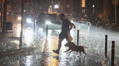 Un hombre y su perro corren a refugiarse de la lluvia.