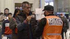 Un polic�a federal argentino comprueba las credenciales de un ciudadano que accede al tren durante la cuarentena