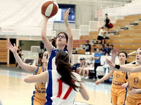 Una  jugadora lanza a canasta en un encuentro por la tarde.