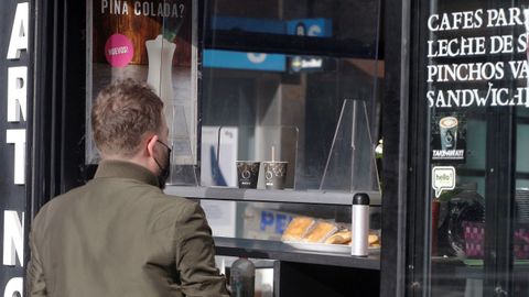 Un hombre compra cafs para llevar en un establecimiento de Gijn, hoy mircoles. Bares, tiendas de ropa, agencias de viaje o inmobiliarias son algunos de los mltiples negocios considerados no esenciales obligados a echar el cierre en Asturias desde este mircoles y durante quince das para tratar de frenar la alta incidencia de la segunda ola de la pandemia de la COVID-19