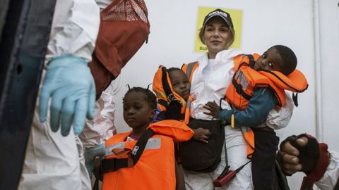 Una voluntaria de la ONG MOAS sostiene en sus brazos a dos peque�os rescatados del mar Mediterr�neo