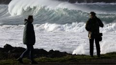 Varias personas pasean ante el fuerte oleaje formado en la costa de Valdovio (A Corua).