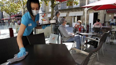 Una camarera limpia una mesa en una terraza de la calle Cardenal, en una fotografa del pasado mes de mayo