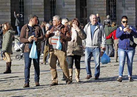 Turistas paseando por el Obradoiro el pasado puente de diciembre mientras comen bocadillos.