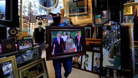 El dueo de una tienda sostiene una fotografia del rey Abdabl II, en Amn