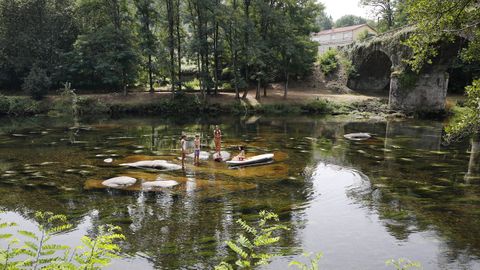 Niños bañándose en el río Avia, en Leiro, con el puente de Esperela al fondo.