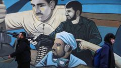Un hombre y una mujer iranes, frente a un mural en Tehern.