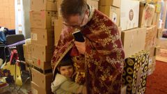 El p�rroco Oleg, con un ni�o, en la iglesia de san Basilio el Grande que sirve de refugio.
