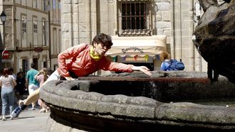Una peregrina se refresca en la fuente de la plaza de Prateras, en Santiago de Compostela