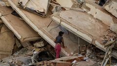 Una mujer mira entre los escombros de un edificio derruido en La Guaira.