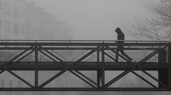 La niebla habitual estos d�as en la comarca de Lemos est� agudizando el efecto de las heladas nocturnas. En la foto, un hombre camina este s�bado por un puente sobre el r�o Cabe en Monforte